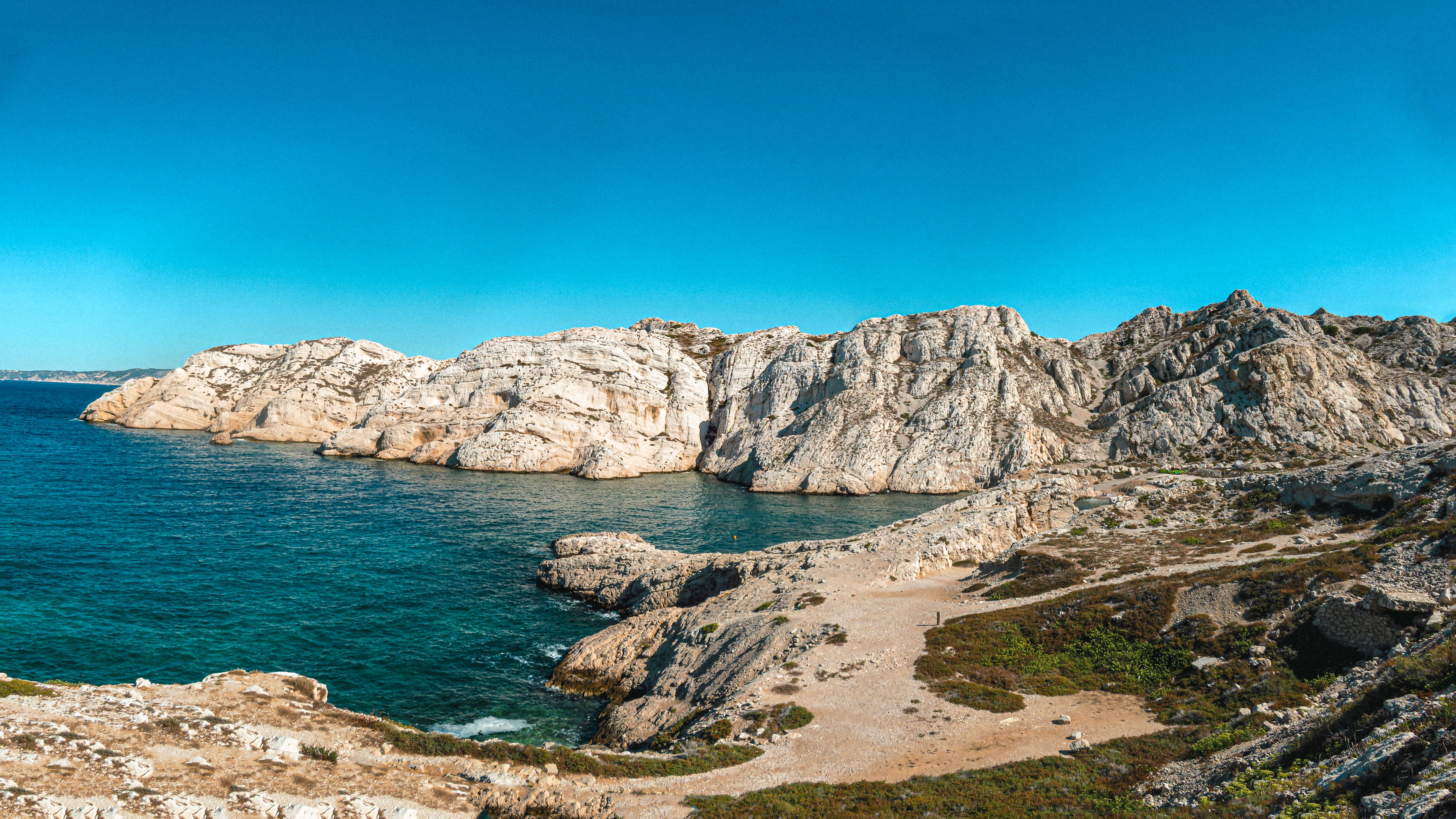 Vue imprenable sur les falaises rocheuses au bord de la mer bleue sous un ciel clair, parfaite pour l'inspiration de voyage.
