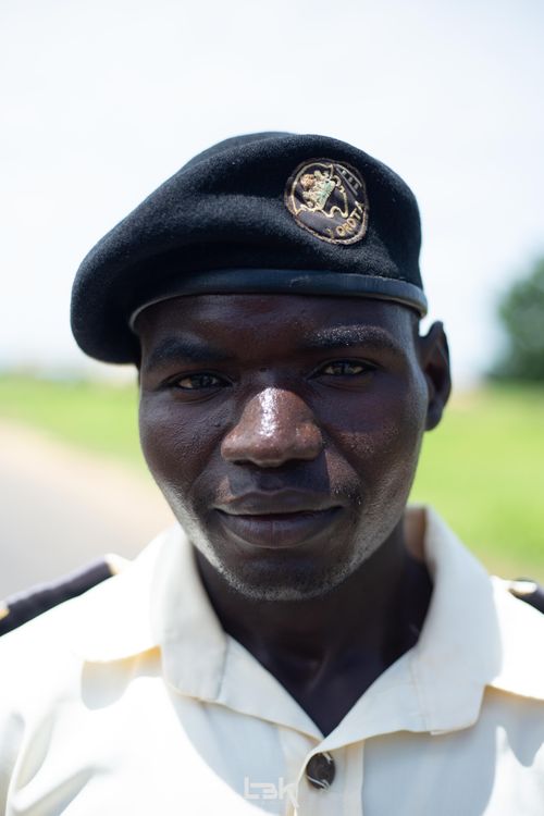 Free Close-up portrait of a male security officer wearing uniform and beret, standing outdoors under bright daylight. Stock Photo