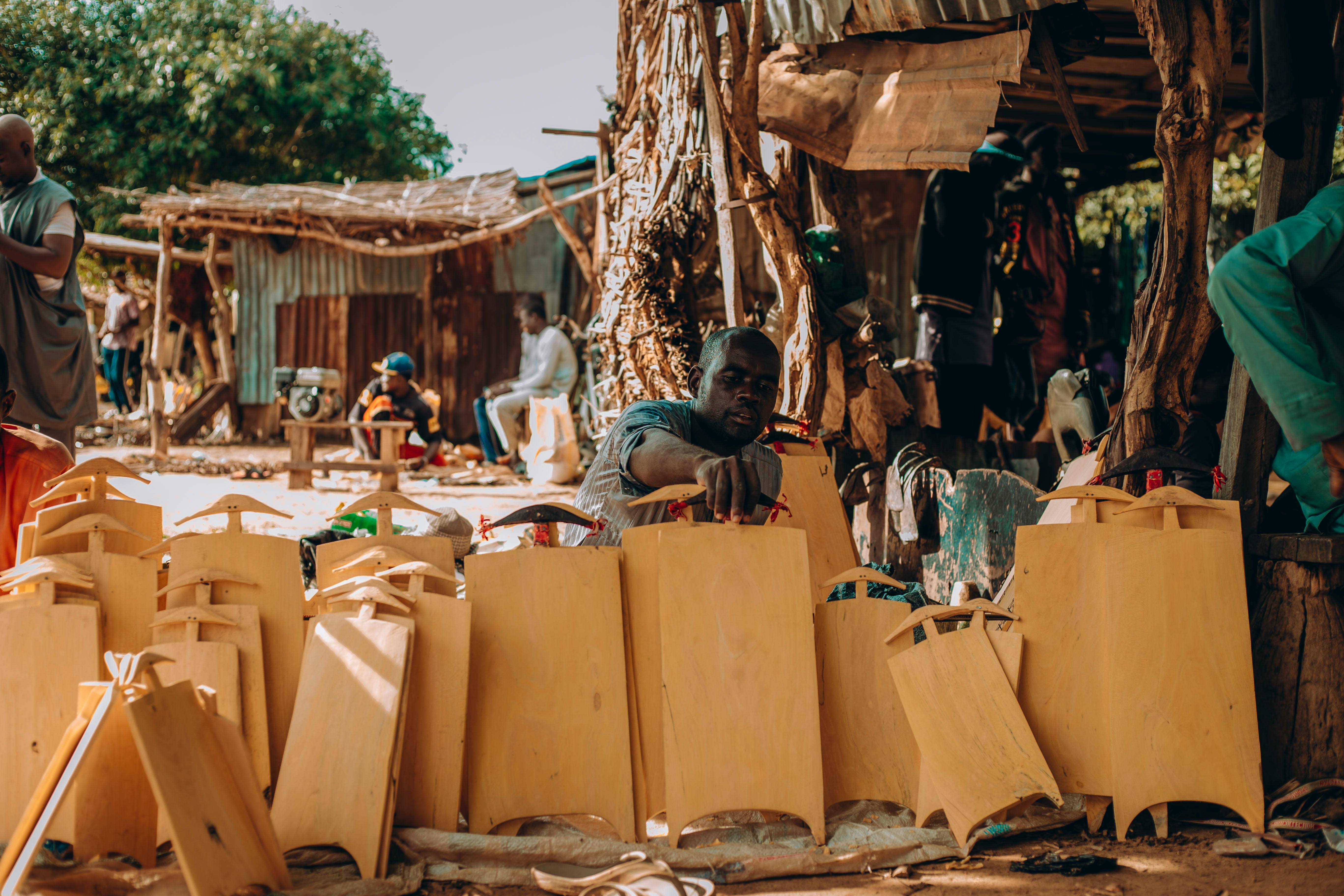 Skilled artisans handcraft traditional Nigerian items in a vibrant outdoor market setting, showcasing cultural craftsmanship.