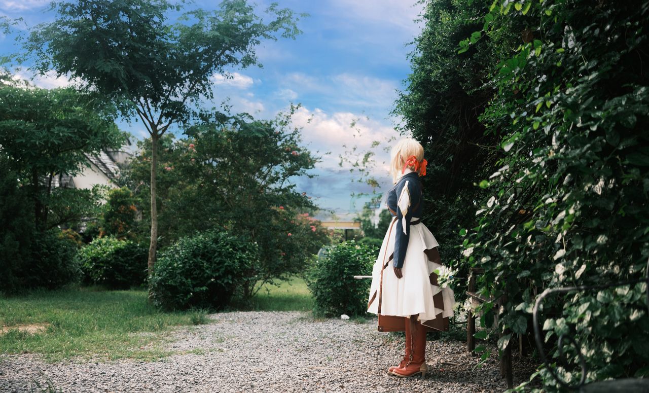 a woman in cosplay attire standing among greenery in a vibrant garden