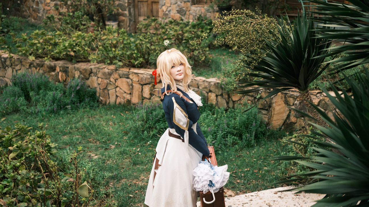 blonde cosplayer in intricate costume posing in lush garden setting