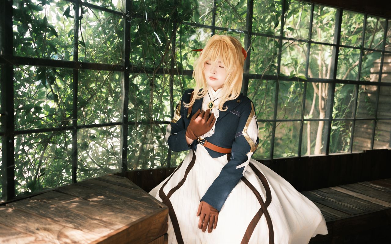 a woman in cosplay attire poses peacefully in a greenhouse surrounded