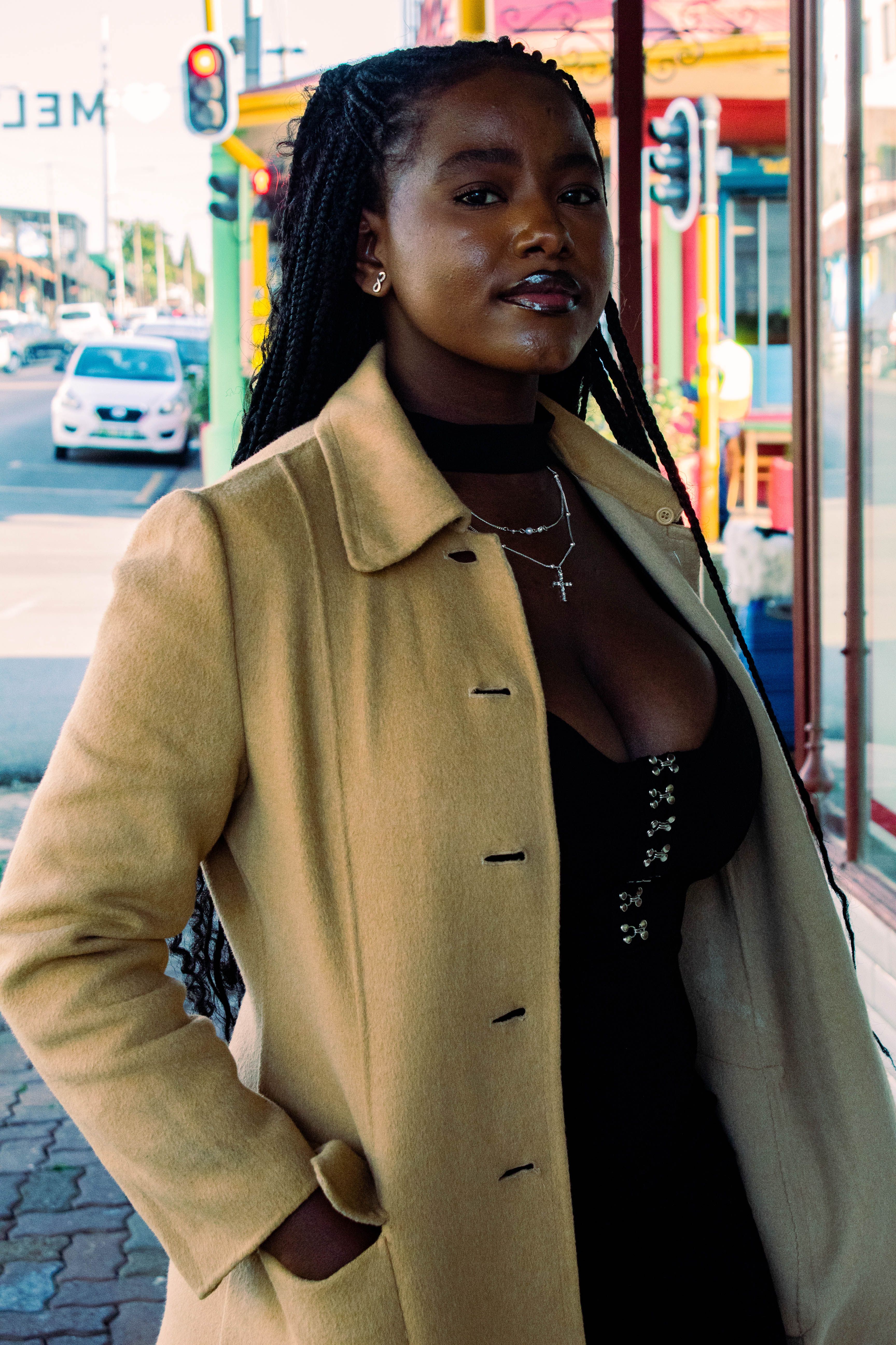 A fashionable woman in a coat strolls through a vibrant urban street.