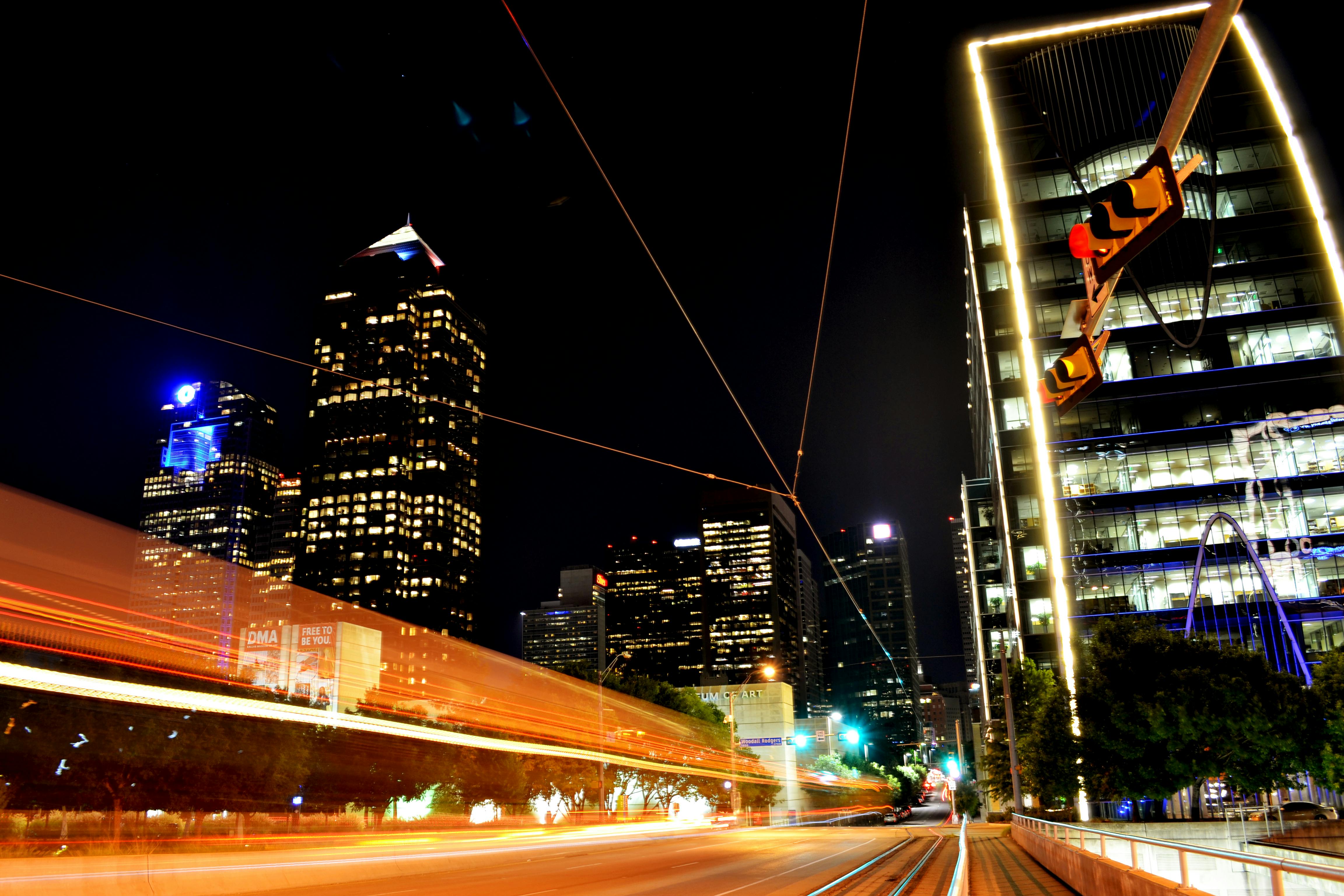 Dynamic night view of Dallas skyline with light trails capturing urban energy and modern architecture.