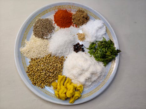 A colorful display of Indian spices and herbs on a circular plate viewed from above.