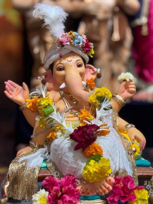 Free Vibrant image of a Ganesh idol richly decorated with colorful flowers and intricate details. Stock Photo