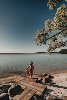 一名女子在木码头上摆姿势，岩石与晴朗的天空共同营造出宁静的海滨景象
