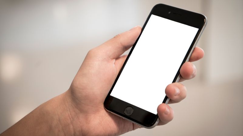 A hand holding a modern smartphone with a blank screen, ideal for design mockups.