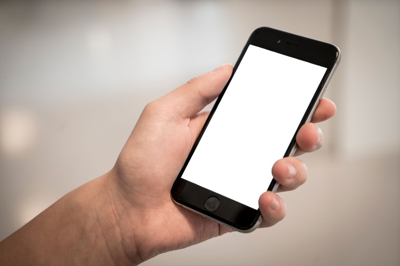Mão segurando um celular com a tela ligada, como quem vai jogar Aviator pelo aplicativo