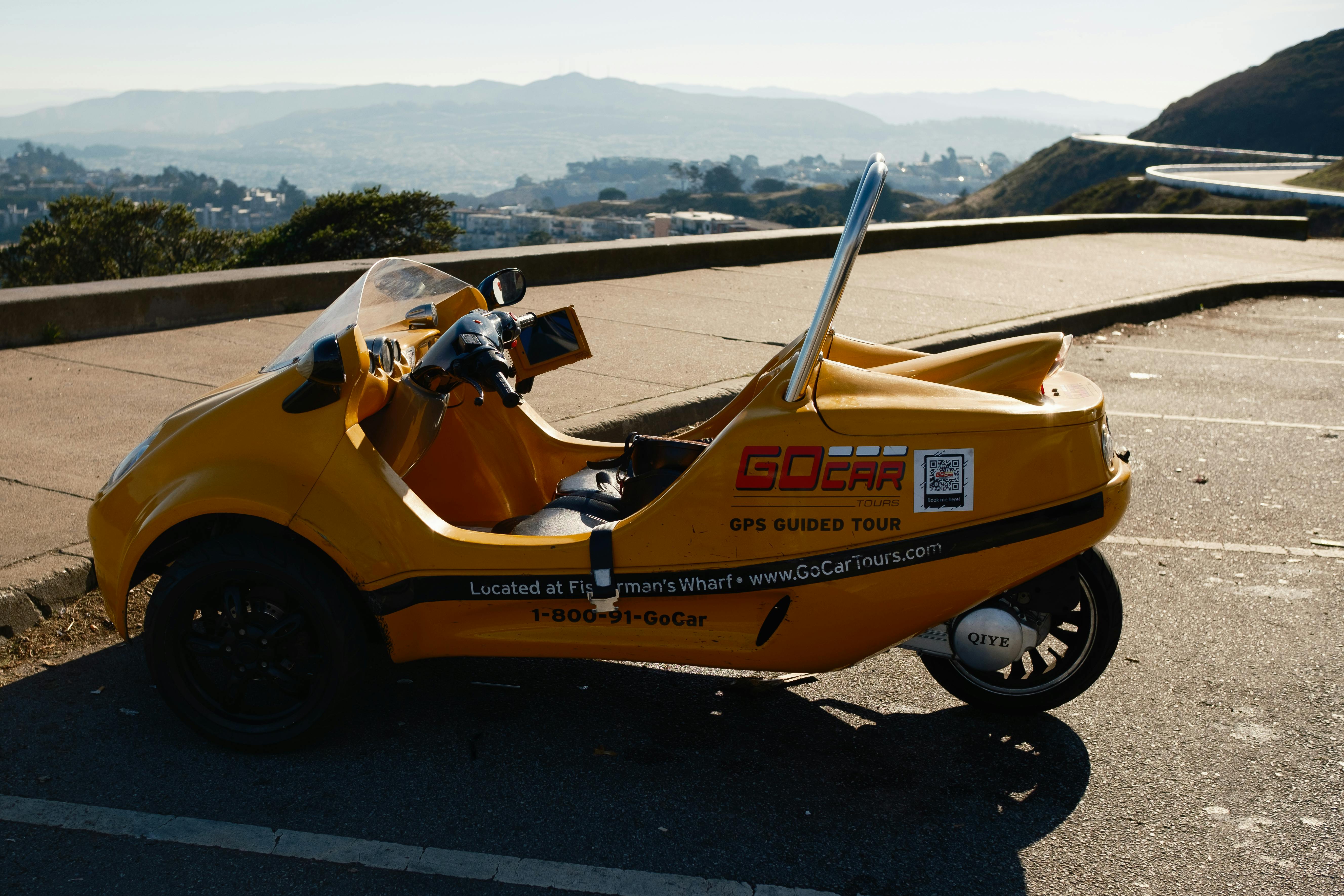 A vibrant yellow GoCar parked with a scenic view in Los Angeles, California.