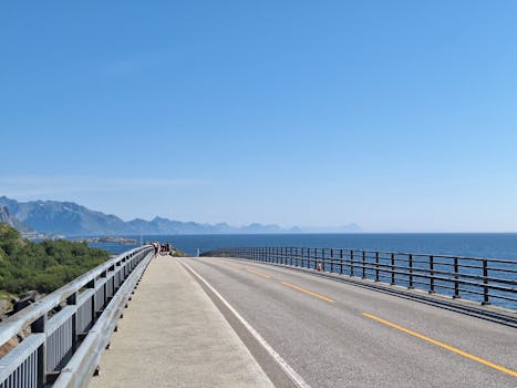 Breathtaking coastal road with ocean and mountains under a clear blue sky.