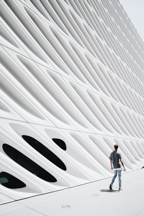 Man Walking on Pathway Near White Structure