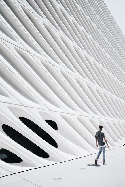 Futuristic facade of The Broad museum with a person walking by in daylight.