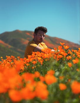 A man sitting in a vibrant California poppy field, capturing the essence of spring.