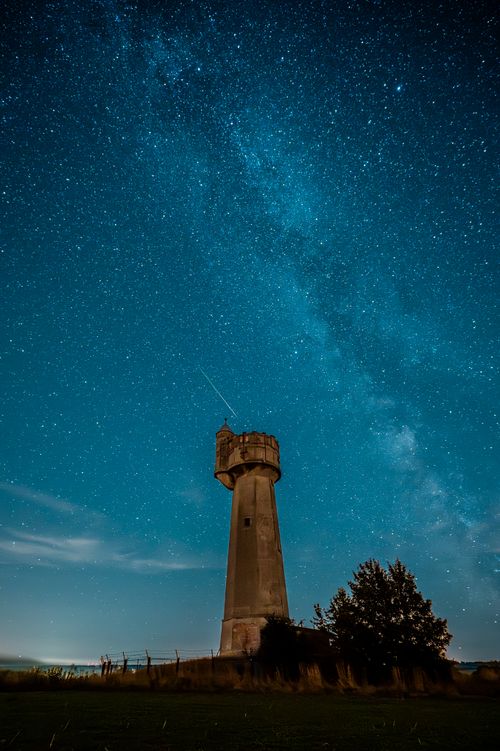 Free A stunning night scene featuring the Milky Way above a solitary water tower. Stock Photo