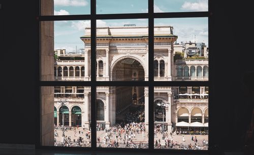 Free Perspective of Milan's Galleria Vittorio Emanuele II through a window, capturing city life outside. Stock Photo