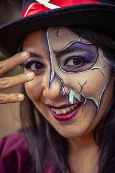 Close-up of a person with vibrant artistic makeup and hat, showcasing cosplay art outdoors.