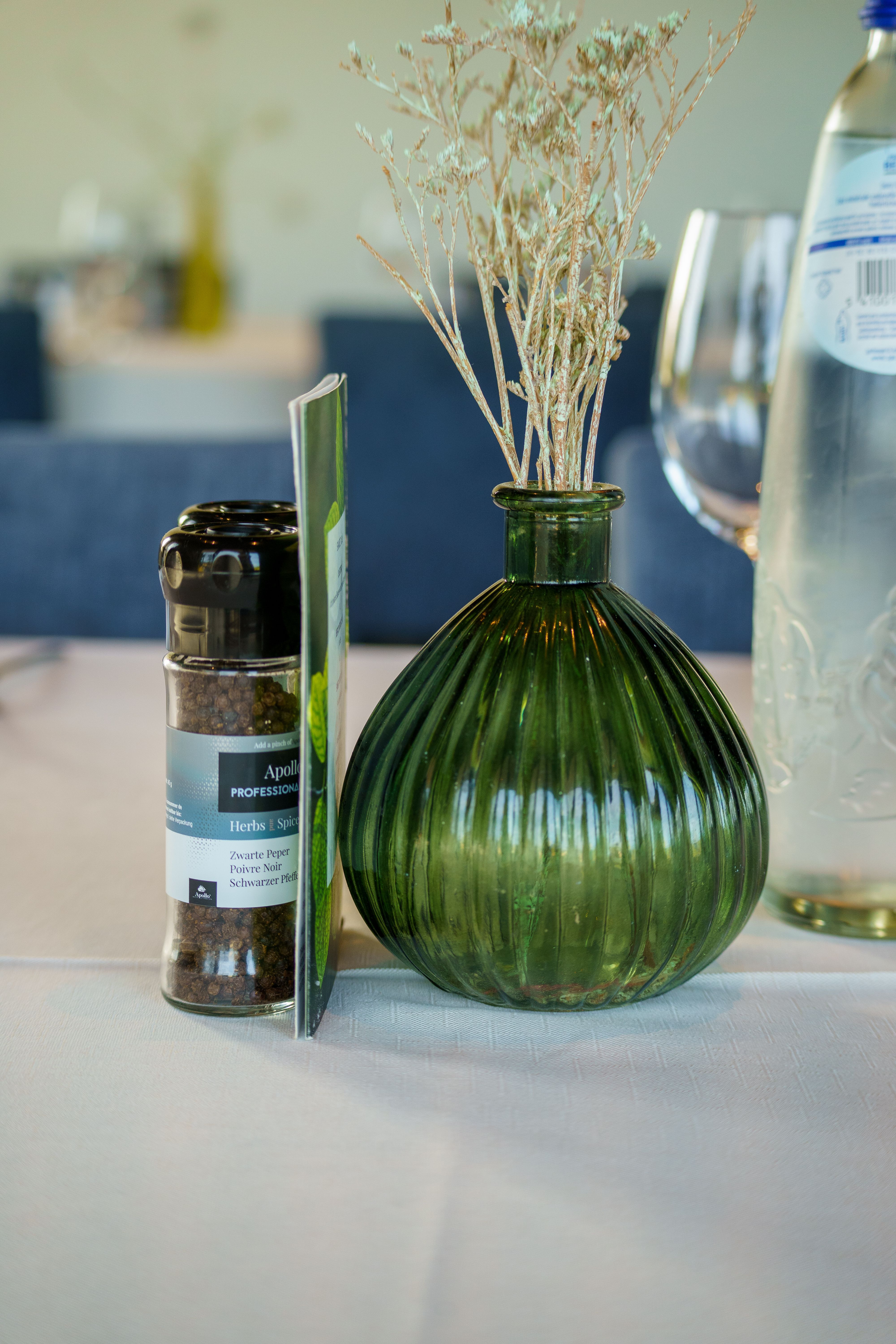 A sophisticated table setting featuring a green vase with dry flower