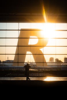 Silhouette of a person at Berlin train station with sunset view of the Fernsehturm and city skyline.