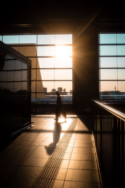Dramatic silhouette of a person walking in Berlin train station during sunset.