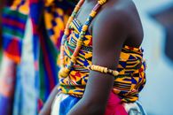 Vibrant traditional Ghanaian attire with beads and kente cloth, highlighting cultural identity.
