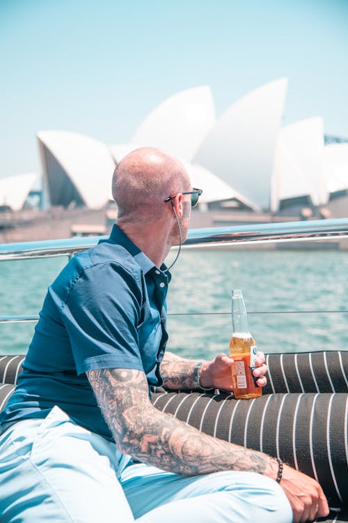 Foco Superficial   Foto De Homem Sentado Segurando Uma Cerveja