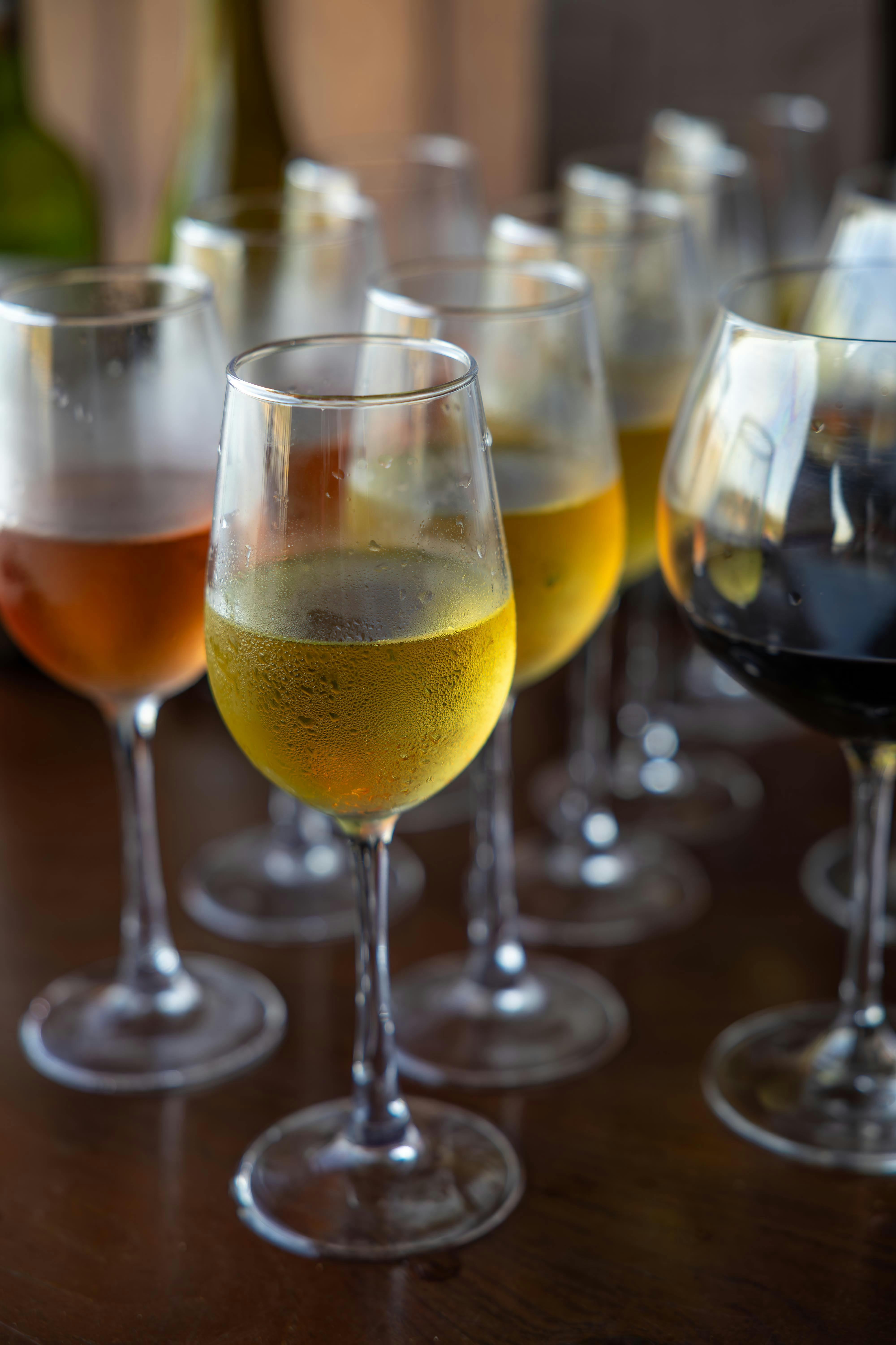 Close-up of various wine glasses filled with white, red, and rosé wines on a wooden table.