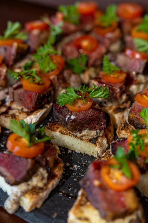 Free Close-up of gourmet bruschetta with beef, cherry tomatoes, and parsley, perfect for culinary enthusiasts. Stock Photo