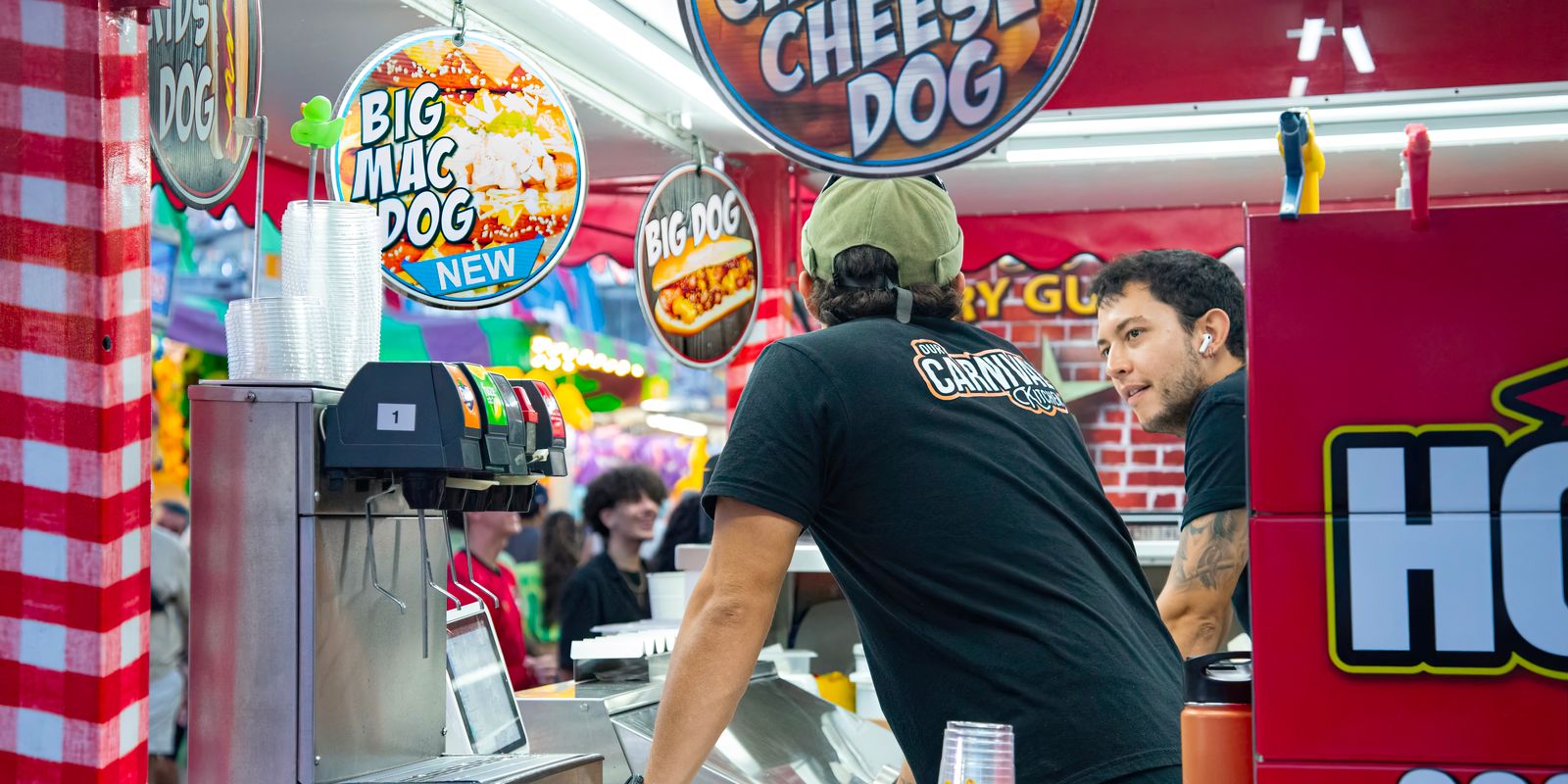 Chili cheese hot dogs being served at a lively outdoor food stand