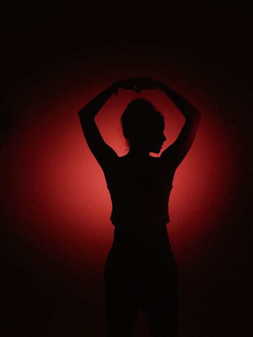 Free A silhouette of a person striking a pose against a bright red gradient backdrop. Stock Photo