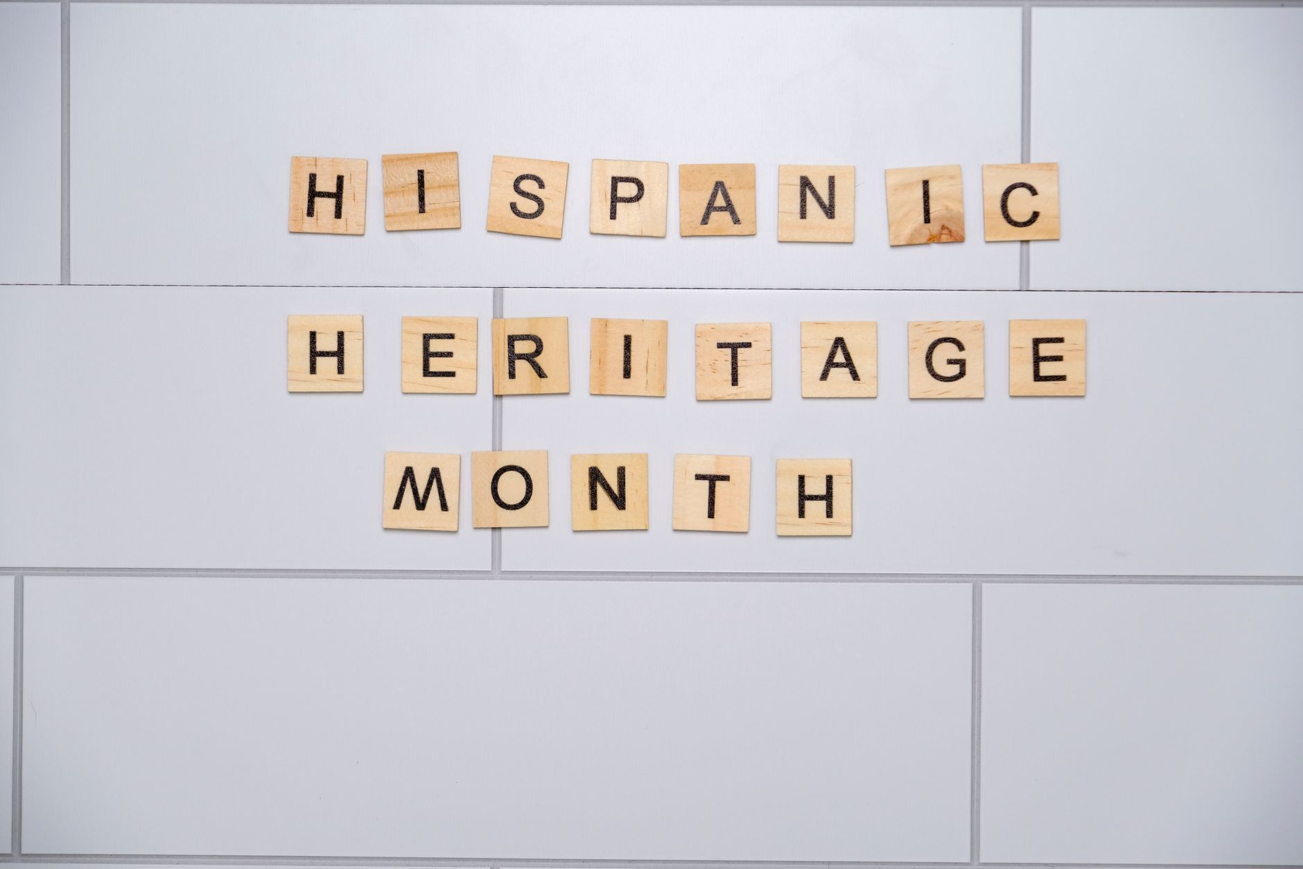 Wooden tiles spelling Hispanic Heritage Month on a tiled wall background.
