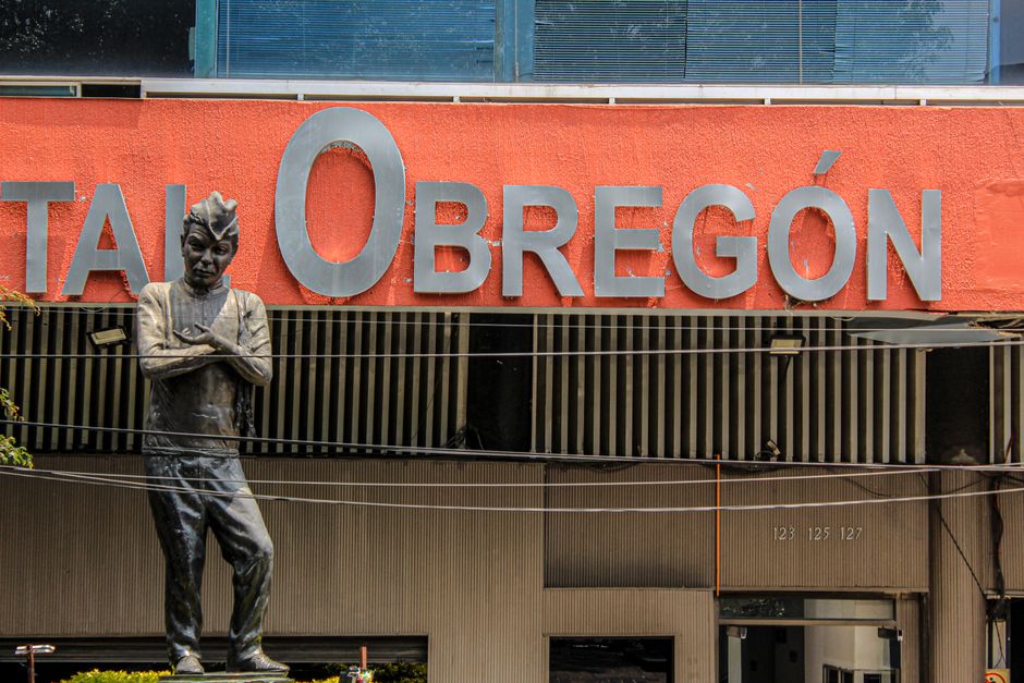 A statue in front of Hospital Obregón, characterized by its red facade in Mexico City.