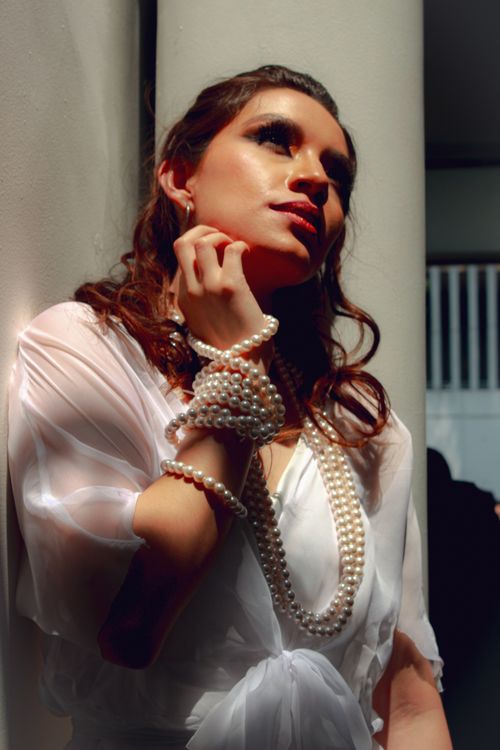 Free Stylish portrait of a woman in pearls and a white dress, exuding elegance and sophistication. Stock Photo