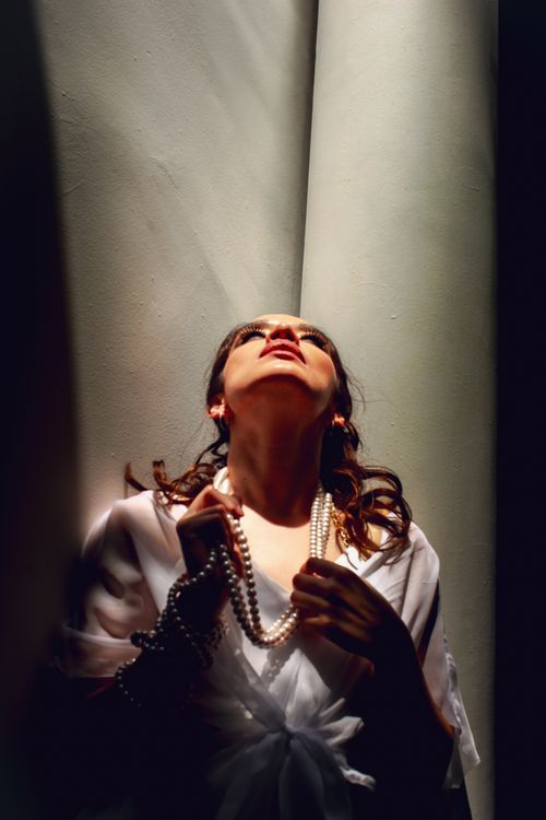 Free Portrait of a woman with a pearl necklace, illuminated dramatically in a classic, sophisticated setting. Stock Photo