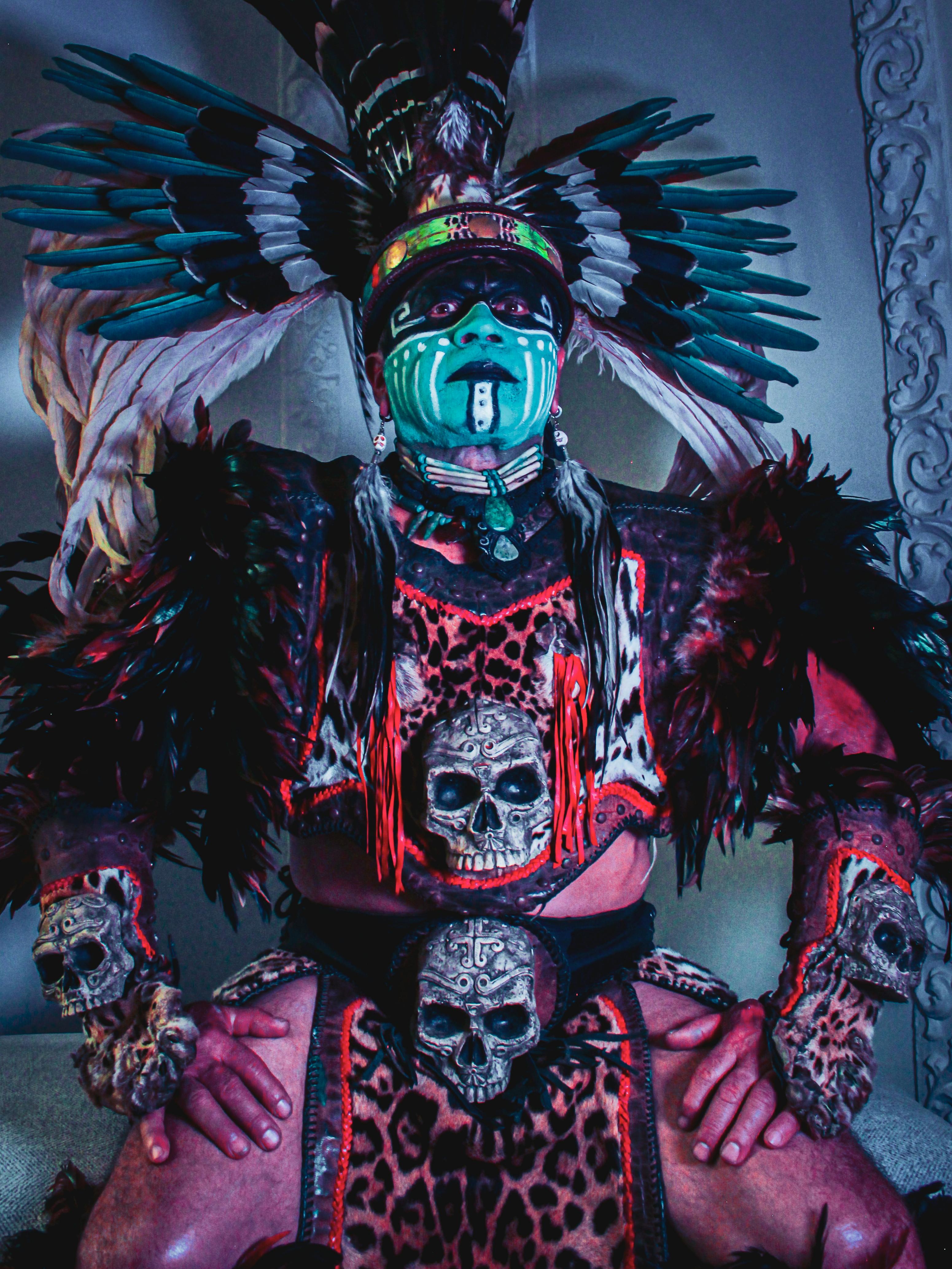 Captivating portrait of an Aztec warrior in full ceremonial attire with vibrant face paint and feathered headdress.