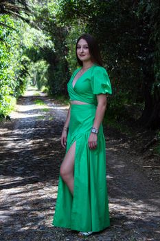 A woman in a green dress poses confidently on a forest path in Santiago de Querétaro, México.