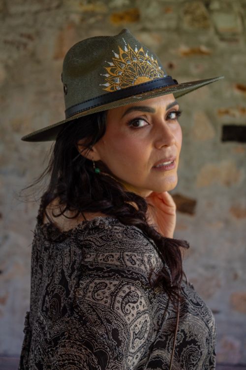 Free Portrait of a sophisticated woman wearing a stylish hat and patterned dress indoors. Stock Photo