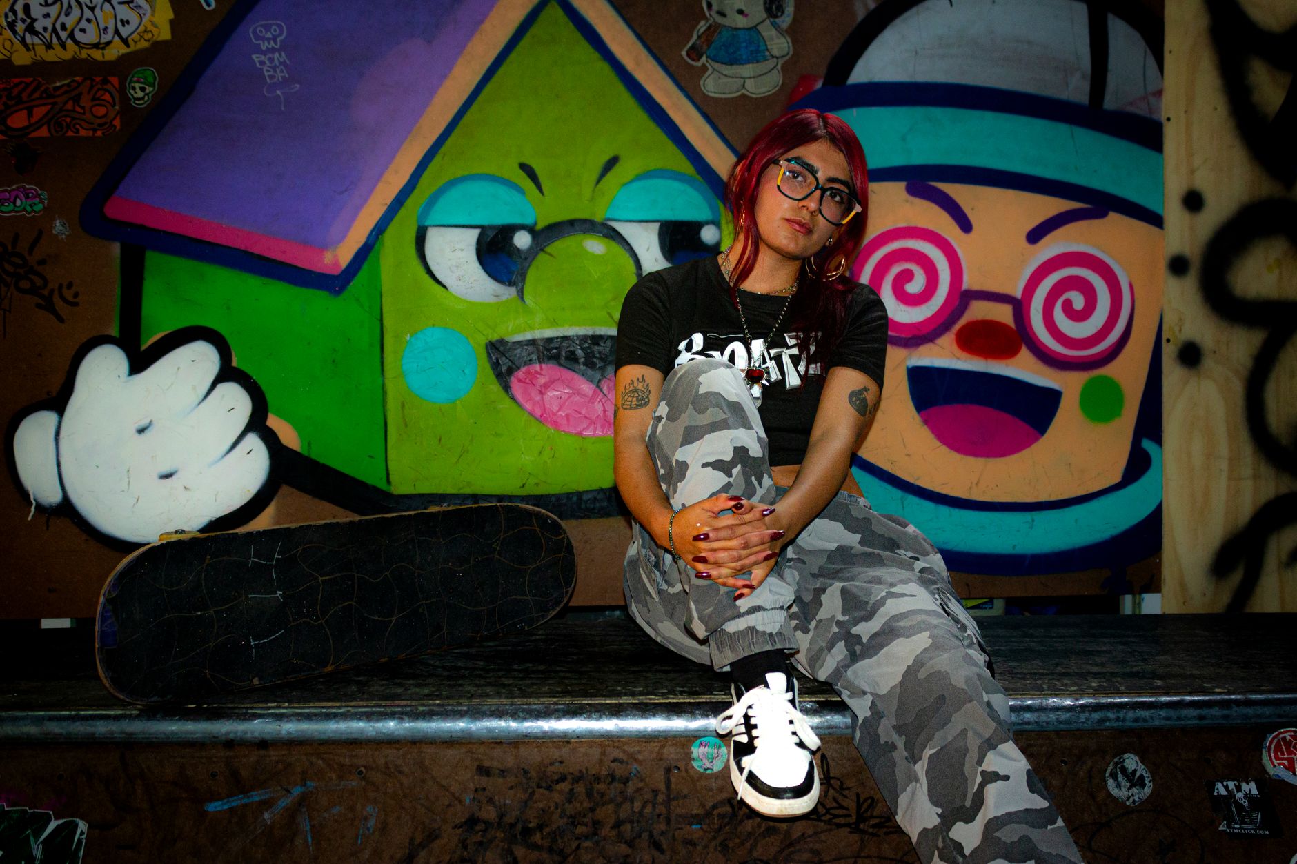 A young woman embraces urban skate culture against a colorful graffiti wall in Toluca, México.