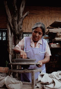 Elderly woman crafting tortillas at an open-air market in Oaxaca, Mexico.