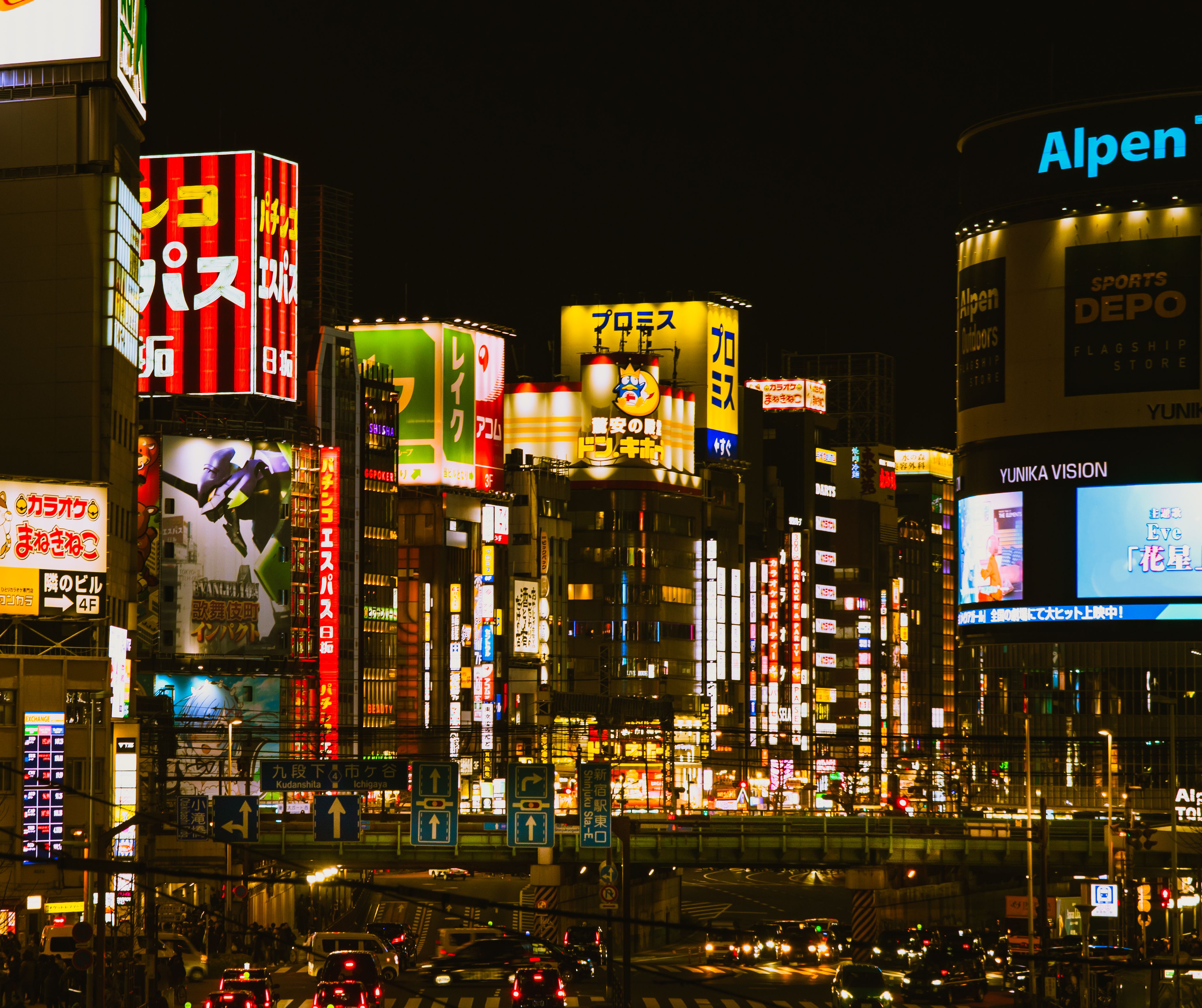 Nighttime Shinjuku street with neon signs and bustling crowds.