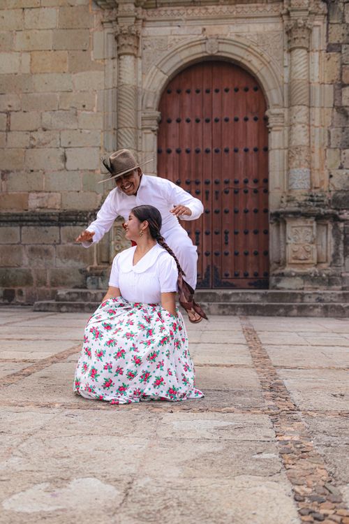 Free A vibrant traditional Mexican dance captured against a historic stone backdrop. Stock Photo