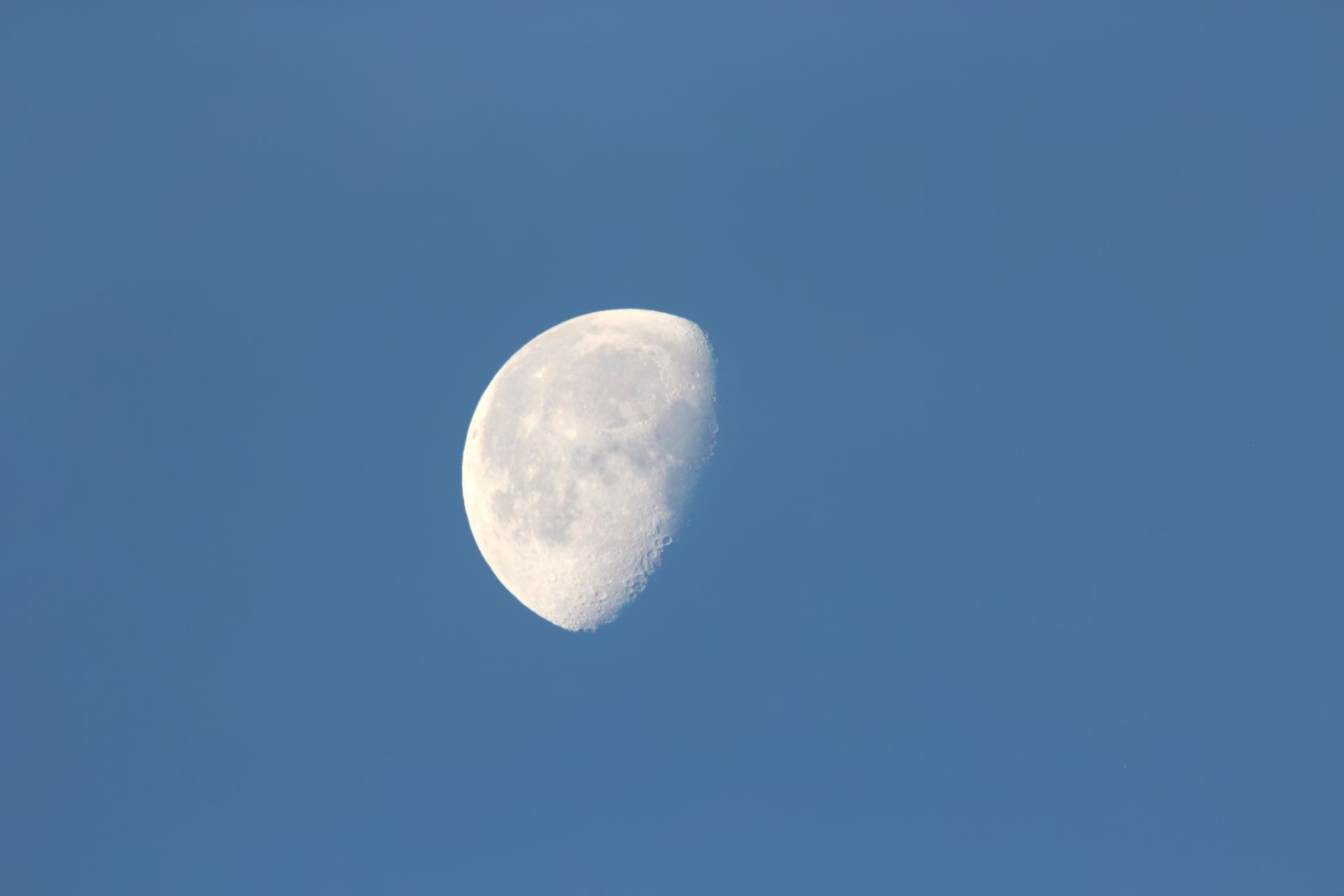 Close-up view of the half moon against a clear blue morning sky.