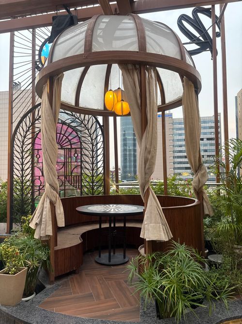 Free Stylish rooftop gazebo with seating area, surrounded by plants and urban buildings. Stock Photo