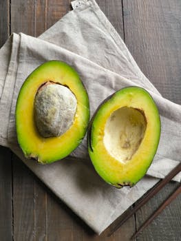Close-up of a ripe avocado split in half on linen cloth over a wooden surface.