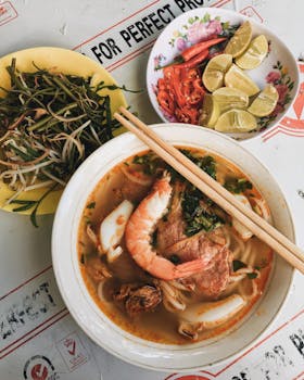 Delicious Vietnamese noodle soup with shrimp and fresh herbs on a street food stall.