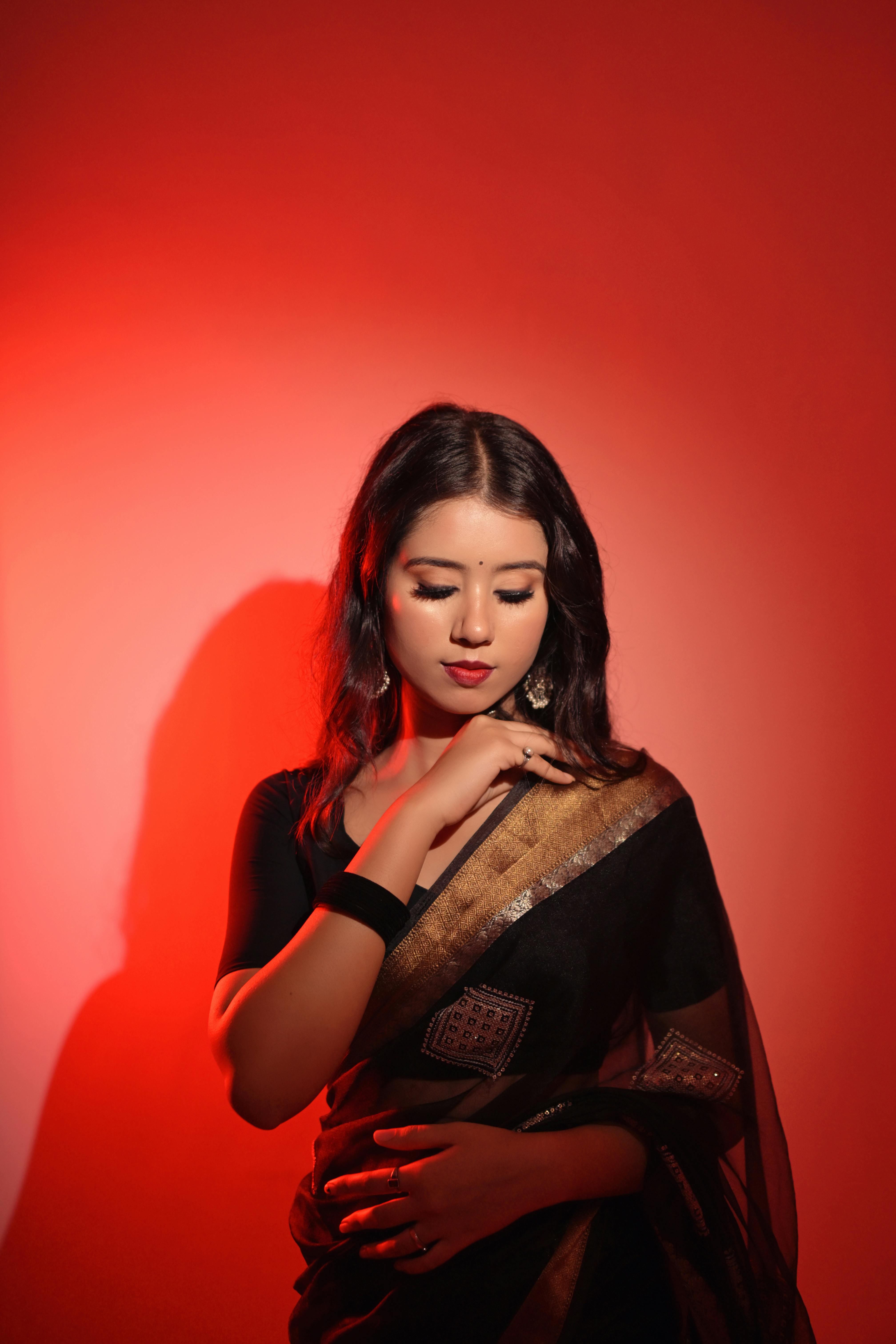 Beautiful portrait of an Indian woman in a traditional black saree with red lighting, showcasing cultural fashion.