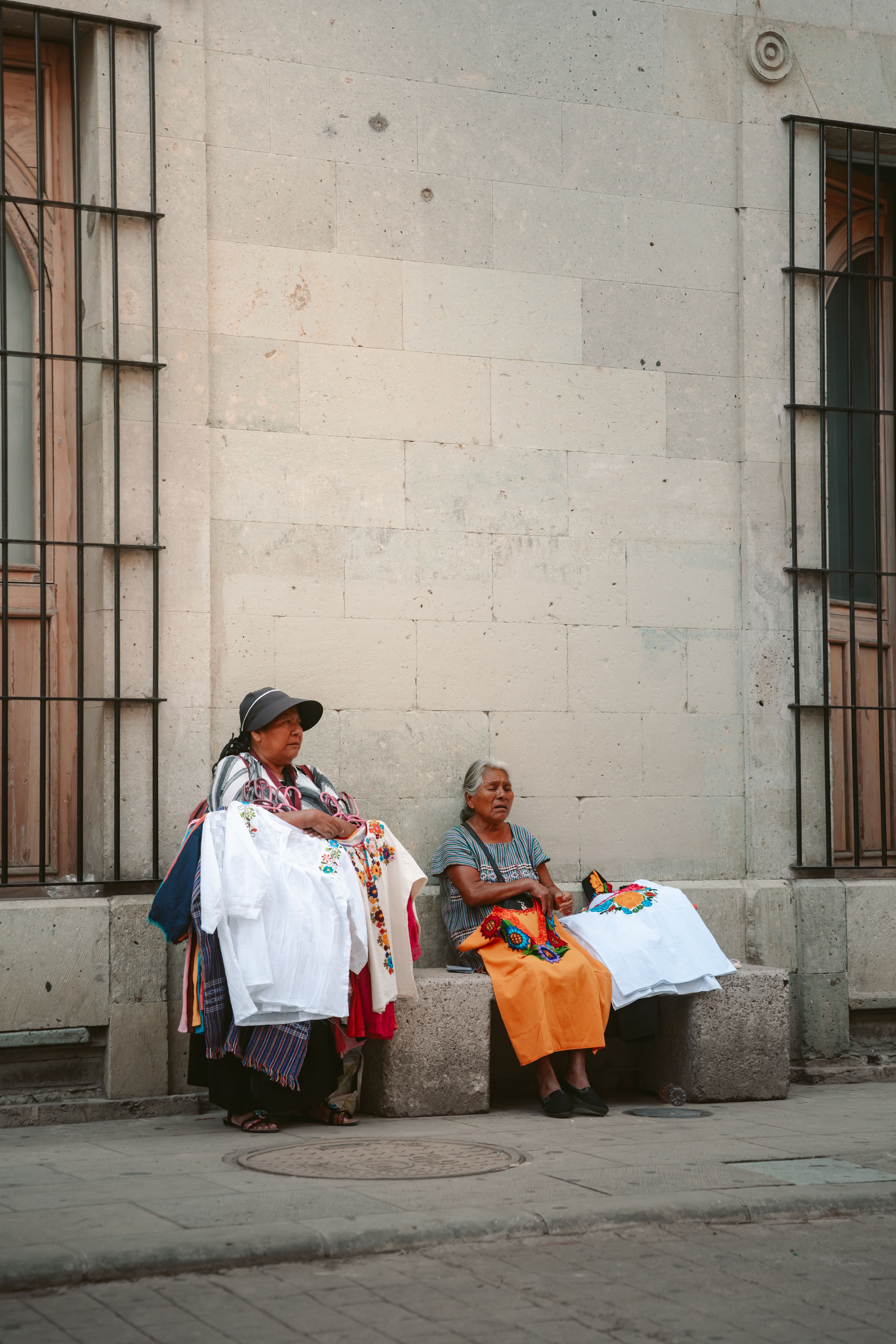 Vendors selling colorful hand-woven textiles on a street in Oaxaca, Mexico