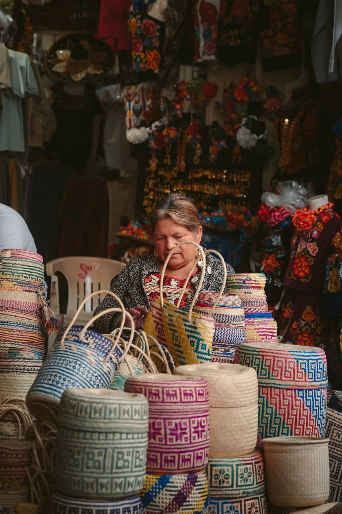 A woman selling traditional woven baskets at a vibrant market in Oaxaca, Mexico.