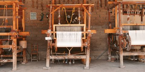 Three wooden looms in an artisan workshop in Oaxaca, Mexico, showcasing local craftsmanship.