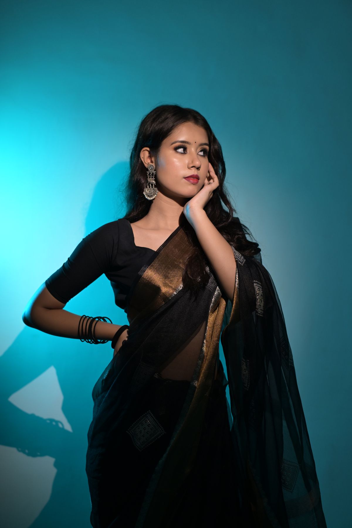 Fashion model wearing a black saree with statement earrings